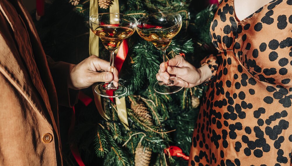 Couple toasting wine glasses near Christmas tree